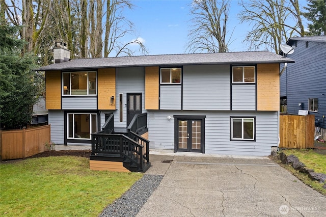 back of property featuring french doors, a yard, a chimney, and fence