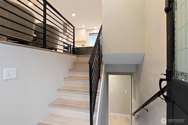 staircase with recessed lighting and wood finished floors