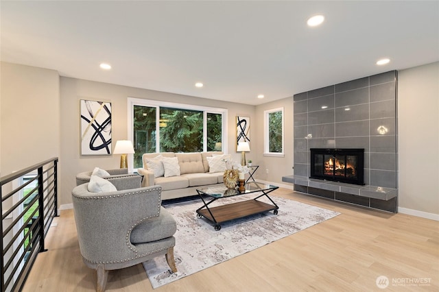 living area with recessed lighting, a tile fireplace, and wood finished floors