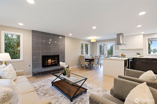 living room with recessed lighting, light wood-type flooring, baseboards, and a fireplace