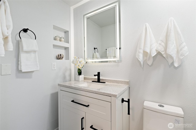 bathroom with vanity, toilet, and built in features