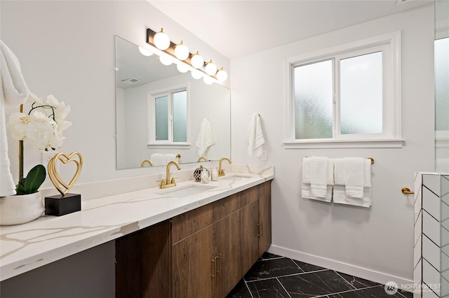 full bathroom with double vanity, baseboards, marble finish floor, and a sink