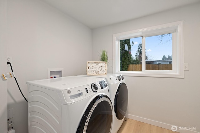 clothes washing area with laundry area, baseboards, light wood-style floors, and separate washer and dryer