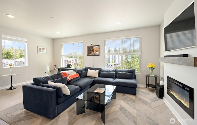 living area featuring recessed lighting, baseboards, and a glass covered fireplace