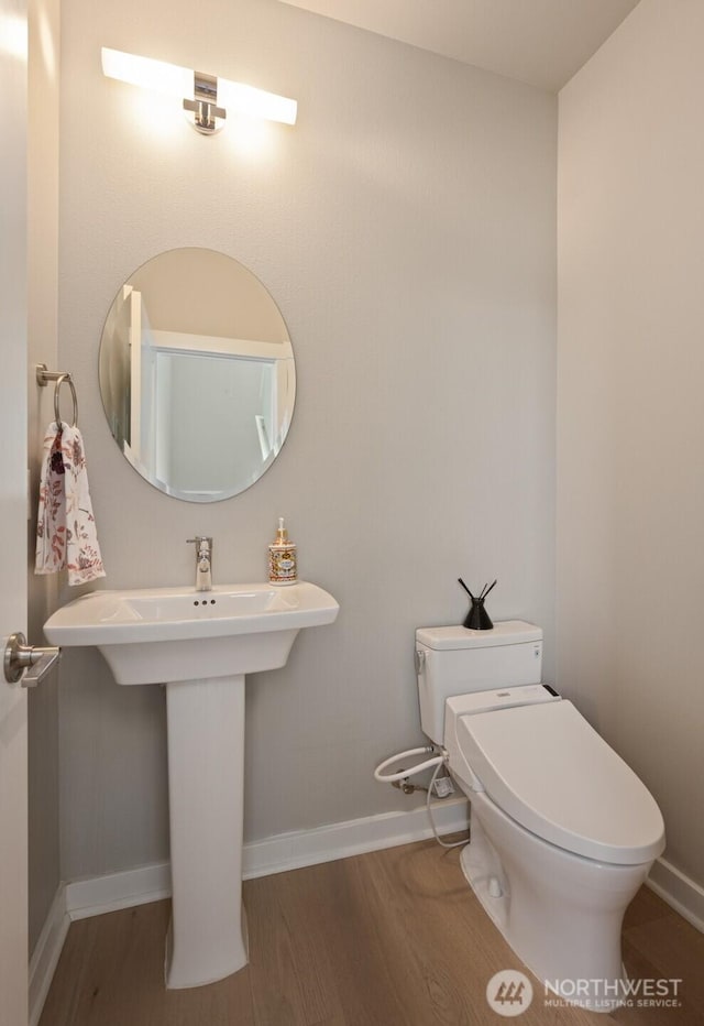 half bath featuring baseboards, toilet, and wood finished floors