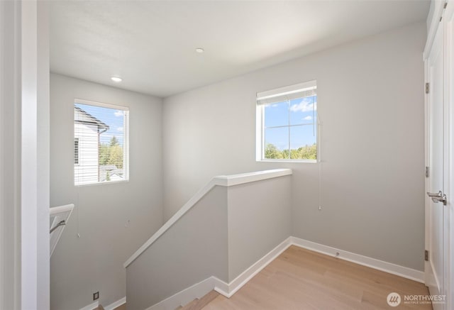 interior space featuring a wealth of natural light, light wood-style flooring, an upstairs landing, and baseboards