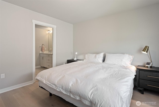 bedroom featuring light wood finished floors, baseboards, and ensuite bathroom