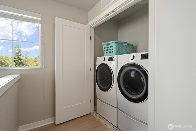 washroom featuring visible vents, laundry area, washing machine and dryer, and light wood-style flooring