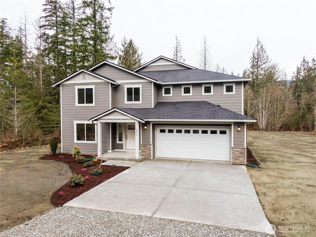 traditional home with a shingled roof, concrete driveway, stone siding, and an attached garage