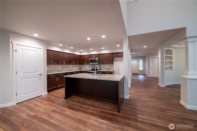 kitchen with dark wood-style flooring, stainless steel appliances, a sink, dark brown cabinets, and ornate columns