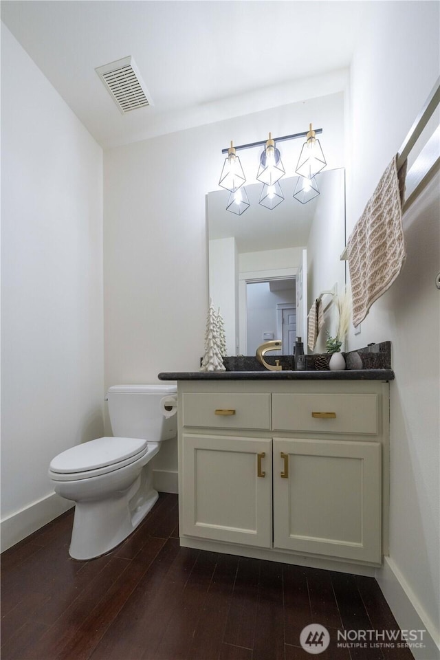 bathroom featuring toilet, wood finished floors, vanity, visible vents, and baseboards