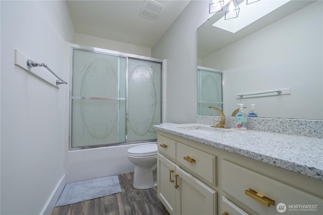 bathroom with toilet, a skylight, wood finished floors, vanity, and visible vents