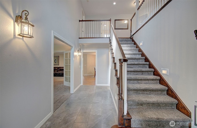 stairway with recessed lighting, french doors, baseboards, and a high ceiling