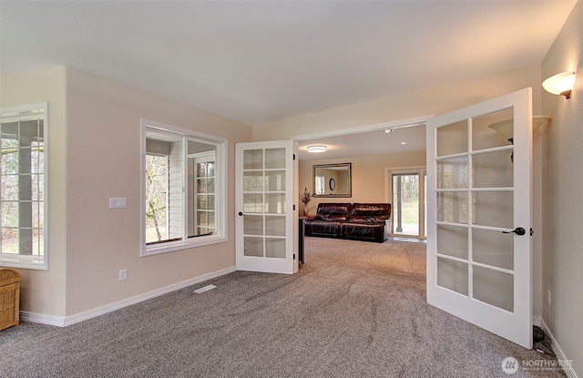 carpeted spare room featuring visible vents, french doors, and baseboards