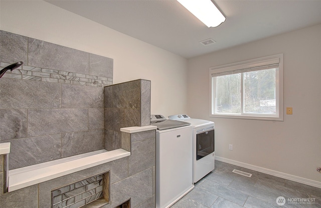 washroom with visible vents, baseboards, laundry area, and washer and clothes dryer