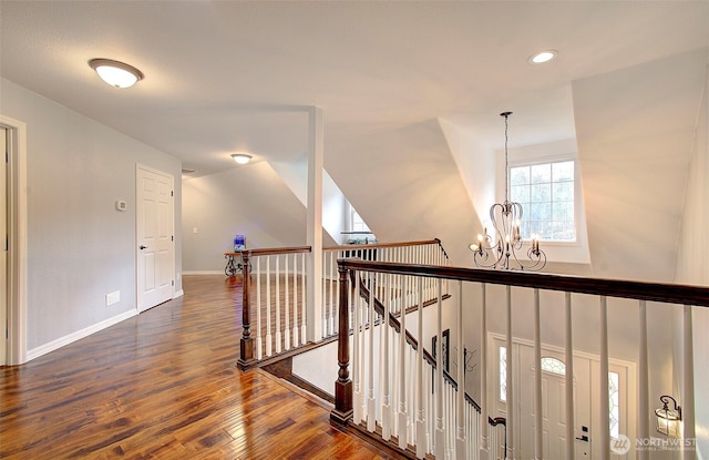 corridor featuring baseboards, an upstairs landing, recessed lighting, wood finished floors, and a notable chandelier