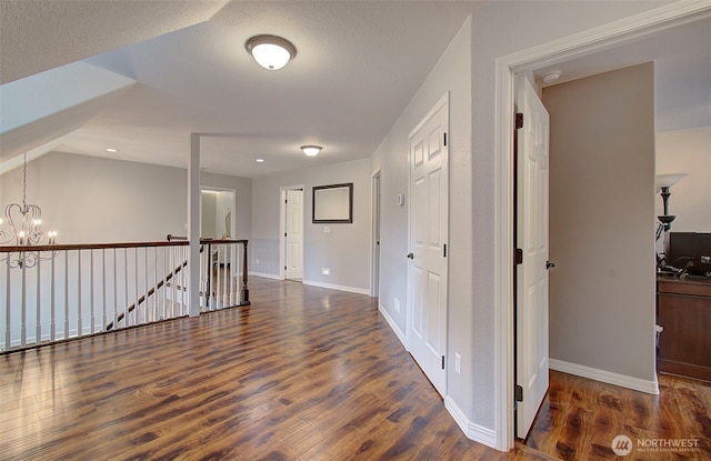 interior space with wood finished floors, baseboards, lofted ceiling, an upstairs landing, and a chandelier