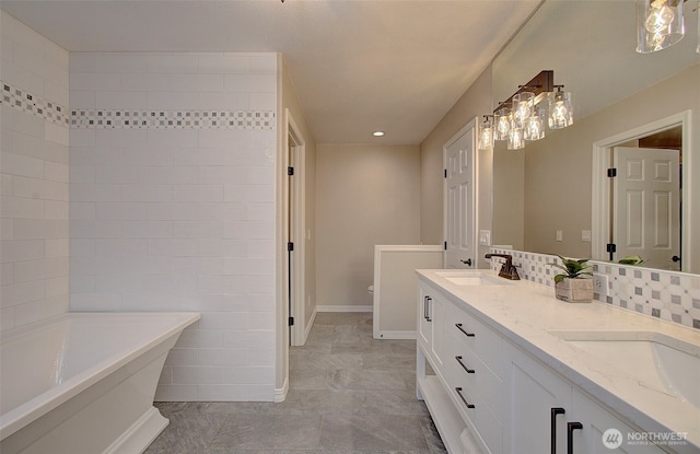 bathroom with a sink, baseboards, a soaking tub, and double vanity