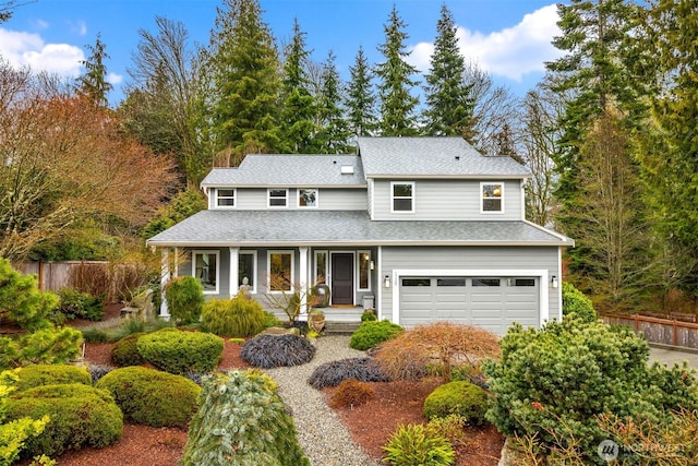 traditional home with an attached garage, fence, covered porch, and a shingled roof