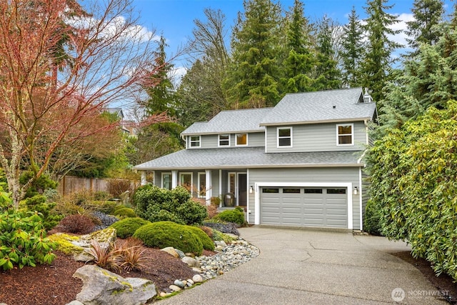 traditional-style home featuring fence, a porch, an attached garage, a shingled roof, and aphalt driveway