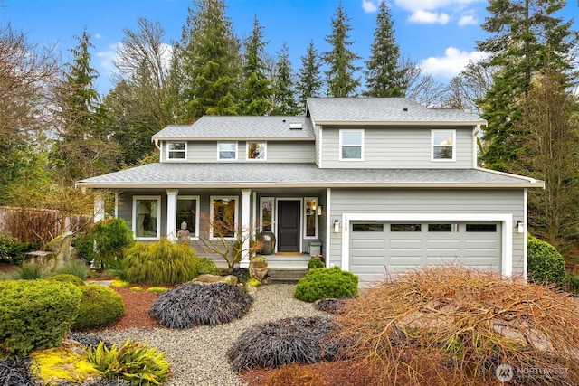 traditional-style home with a porch, a shingled roof, and a garage