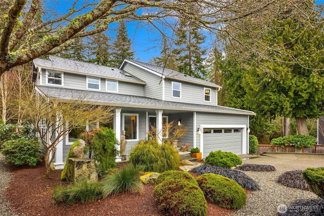 traditional-style house with a porch, a shingled roof, and driveway