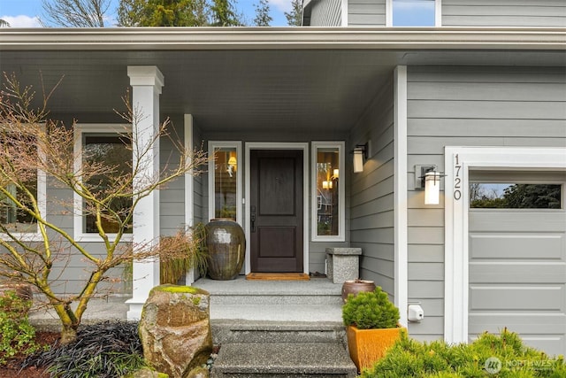 view of exterior entry with a garage and a porch