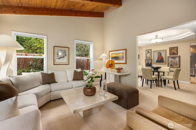 carpeted living room with wooden ceiling, vaulted ceiling with beams, a healthy amount of sunlight, and baseboards