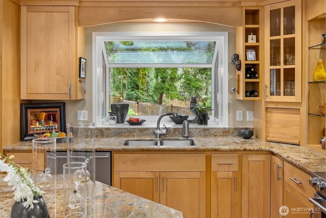 kitchen with appliances with stainless steel finishes, light stone countertops, glass insert cabinets, and a sink