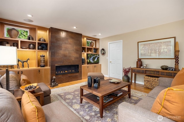 living room with recessed lighting, wood finished floors, baseboards, and a tile fireplace