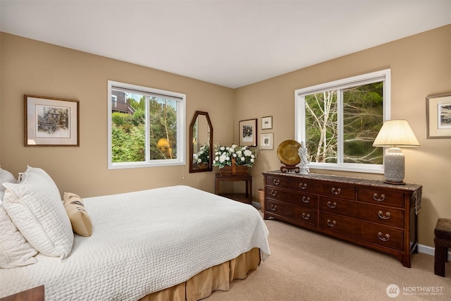 bedroom with light carpet, multiple windows, and baseboards