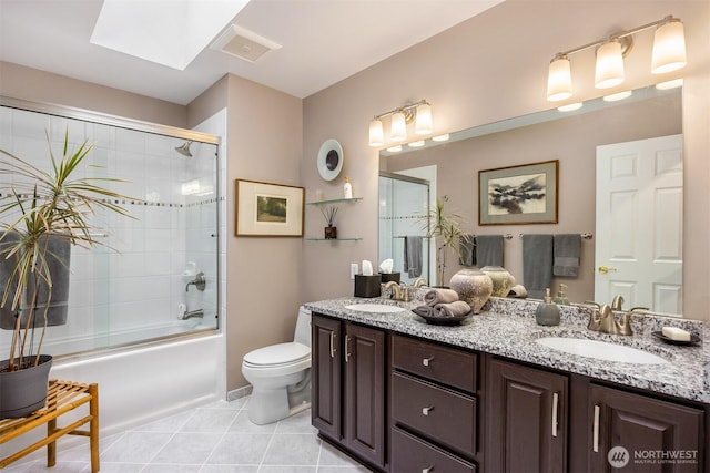 bathroom featuring tile patterned flooring, double vanity, a skylight, and a sink