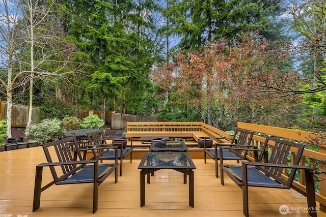 deck featuring an outdoor living space with a fire pit and fence