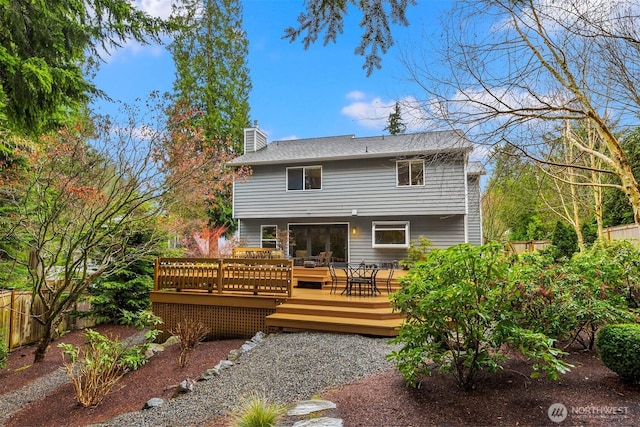 back of house with a deck, a chimney, and fence