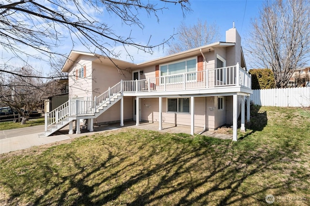 back of property featuring stairway, fence, a chimney, a patio area, and a lawn