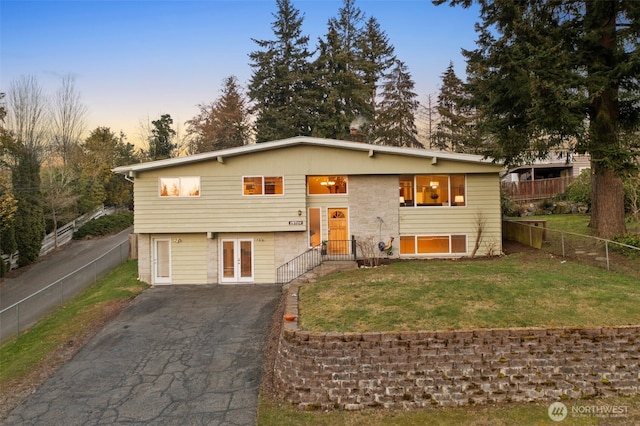 raised ranch with a yard, driveway, french doors, and fence