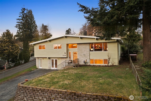 split foyer home with aphalt driveway, fence, and a front lawn