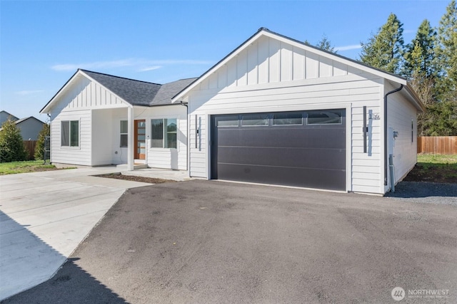 modern farmhouse with fence, board and batten siding, and roof with shingles