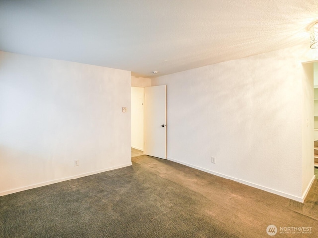 spare room featuring baseboards and dark carpet