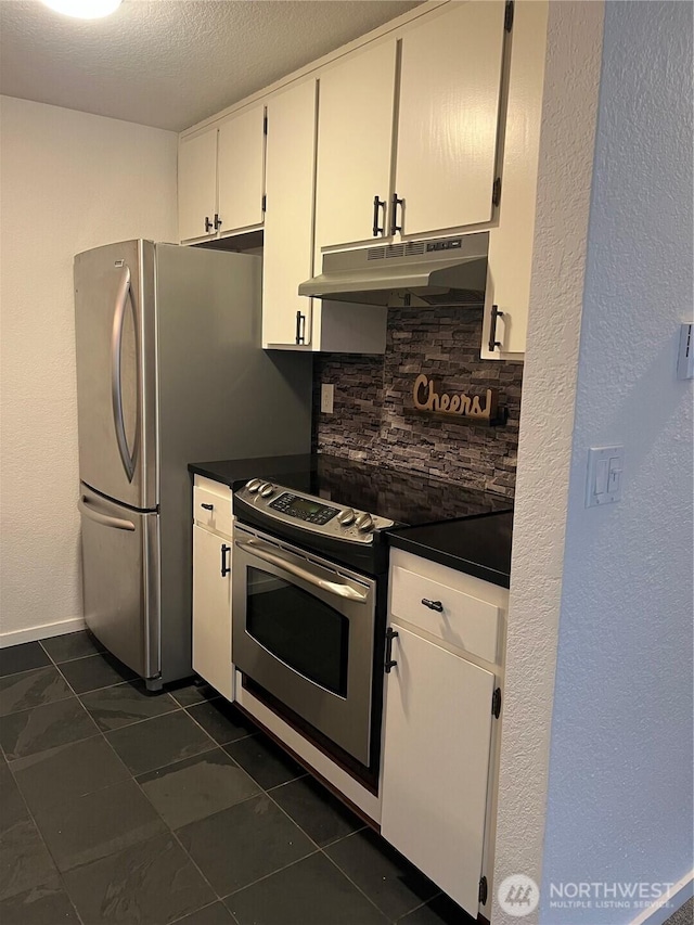 kitchen featuring under cabinet range hood, stainless steel appliances, white cabinets, tasteful backsplash, and dark countertops