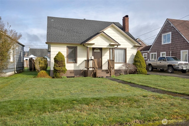 view of front of house featuring a chimney, a shingled roof, and a front yard