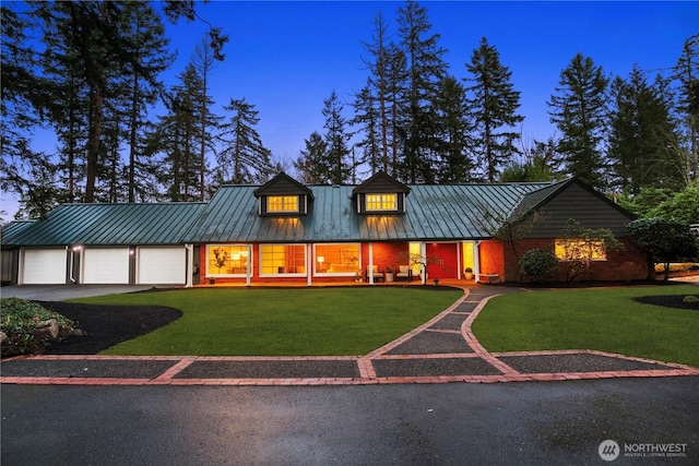 view of front of house featuring a garage, a standing seam roof, metal roof, and a yard