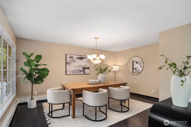 dining area with a chandelier, baseboard heating, and wood finished floors