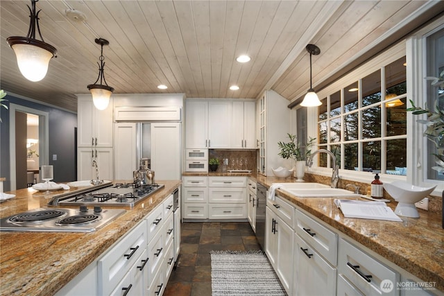 kitchen with tasteful backsplash, stainless steel appliances, stone finish floor, white cabinetry, and a sink