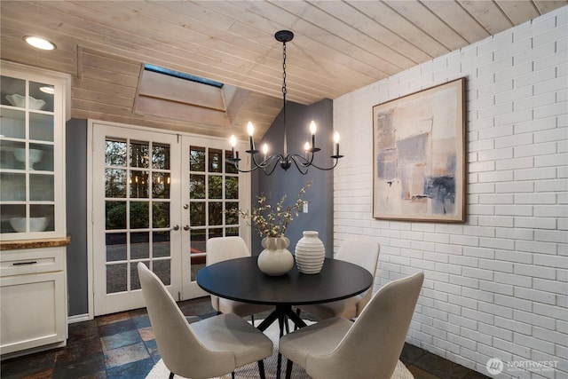 dining area featuring wooden ceiling, brick wall, stone tile floors, and french doors