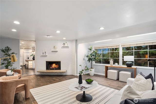 living area featuring a brick fireplace, wood finished floors, and recessed lighting