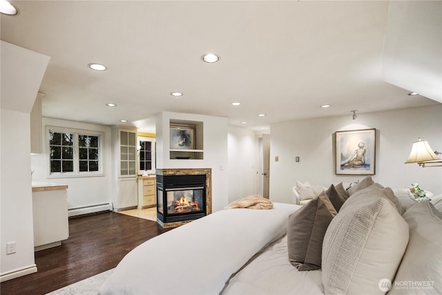 bedroom with recessed lighting, a baseboard radiator, wood finished floors, and a multi sided fireplace