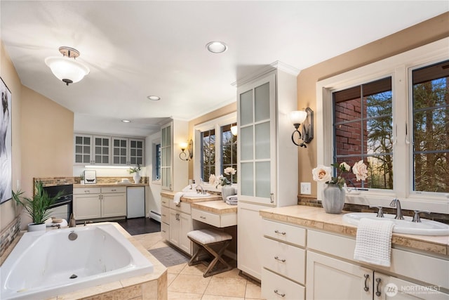 bathroom with tile patterned flooring, a tub with jets, two vanities, and a sink