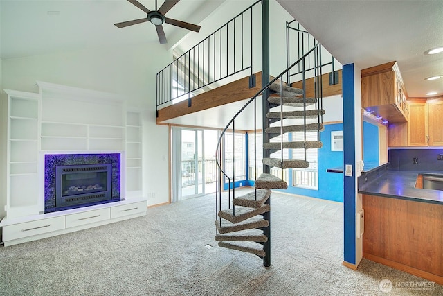 stairway with ceiling fan, high vaulted ceiling, recessed lighting, carpet floors, and a glass covered fireplace