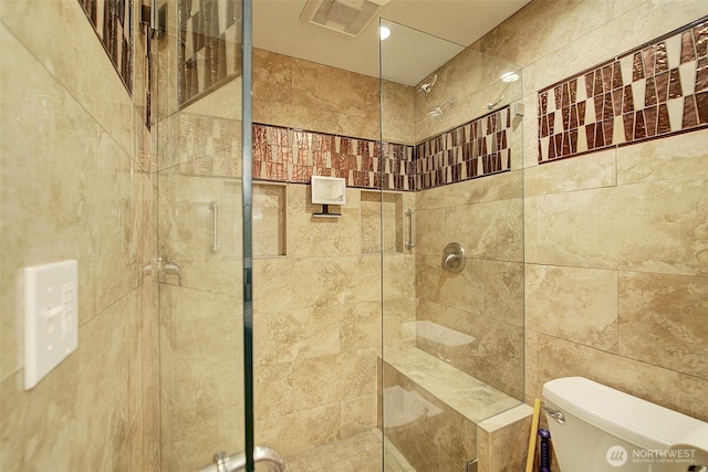 bathroom featuring toilet, a shower stall, and visible vents